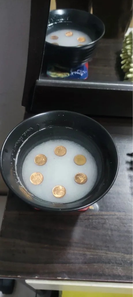 安忍水制作步骤图：在装有粗盐和水的玻璃碗中，将6枚铜币（或1分钱硬币）围成一圈摆放，用于化解五黄煞。