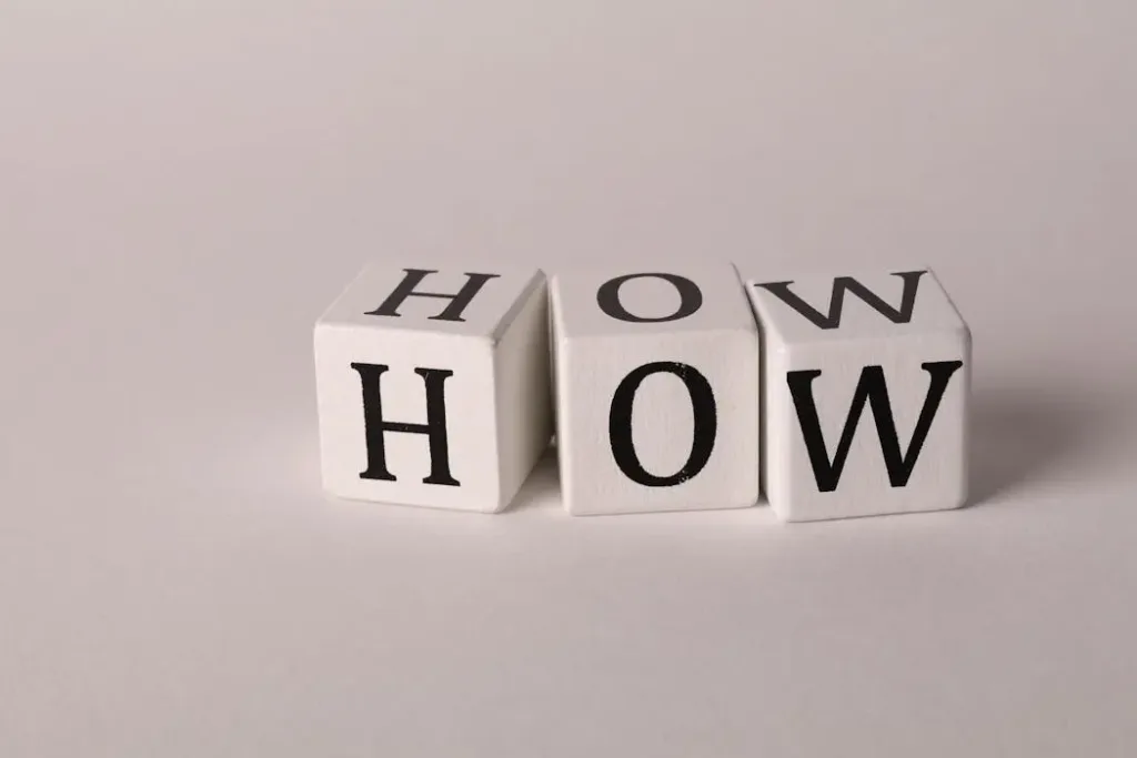 白色木制字母块拼成“HOW”单词，象征寻找风水改运方法与具体实操步骤