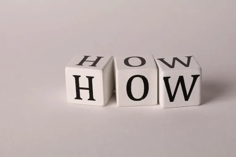 白色木制字母块拼成“HOW”单词，象征寻找风水改运方法与具体实操步骤
