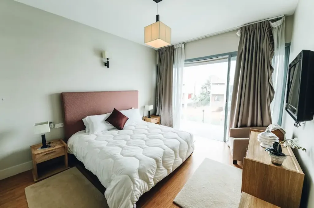 卧室床位与窗户风水布局 - 猫哥风水|马来西亚风水・紫微斗数・奇门遁甲 一间采光充足的现代卧室,床铺摆放在靠近落地窗的位置,展示了自然光对卧室风水的影响