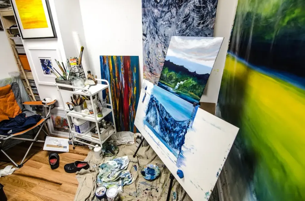 杂乱的工作室风水隐患 - 猫哥风水|马来西亚风水・紫微斗数・奇门遁甲 一个堆满画作、颜料罐和杂物的凌乱画室角落,展示了杂物堆积如何导致气场停滞