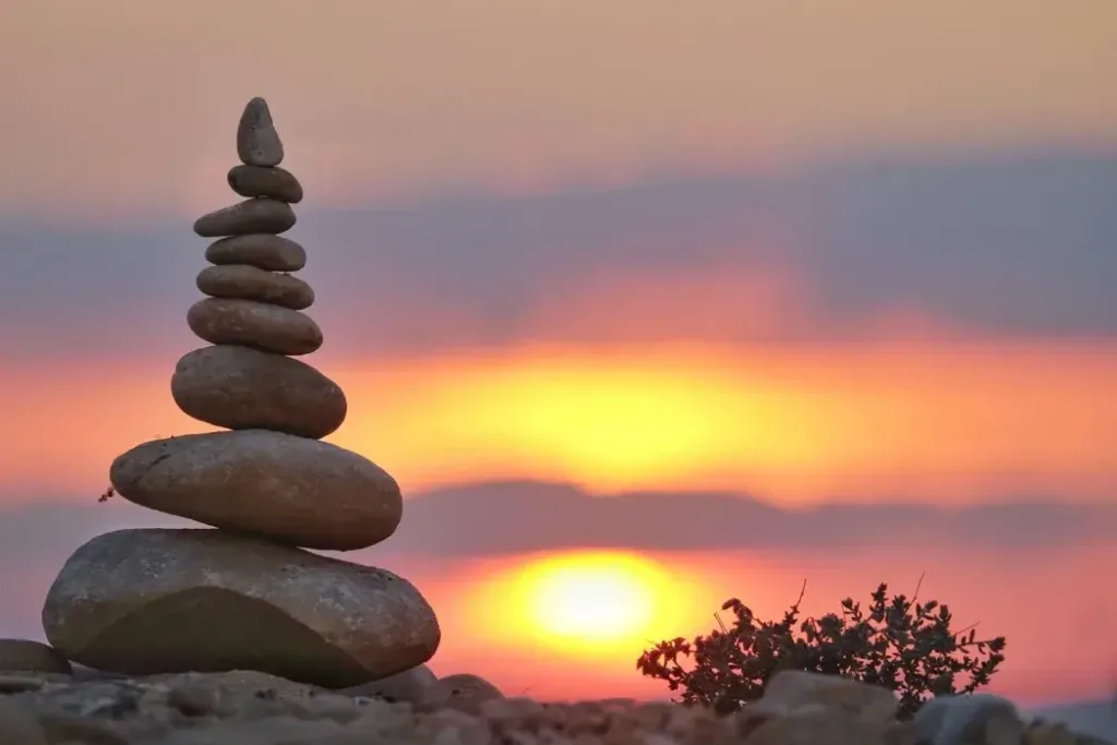 Earth Element Feng Shui Stability - 猫哥风水|马来西亚风水・紫微斗数・奇门遁甲 A stack of balanced stones against a sunset, representing the Earth element's grounding energy in Feng Shui.