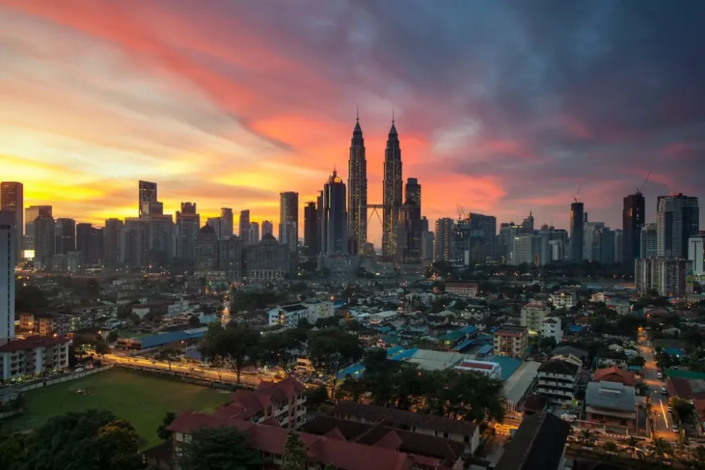 马来西亚吉隆坡双峰塔（KLCC）的壮丽黄昏景色。太阳逐渐落下，象征着吉隆坡的真实太阳时间比标准的 GMT+8 时间慢约 1 小时，这对八字和紫微斗数排盘的准确性至关重要。