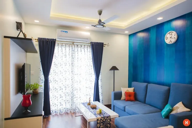 A modern living room with a striking deep blue feature wall and matching blue sofa. In Feng Shui, blue represents the Water element, which brings wisdom, abundance, and a calming Yin energy to the space.