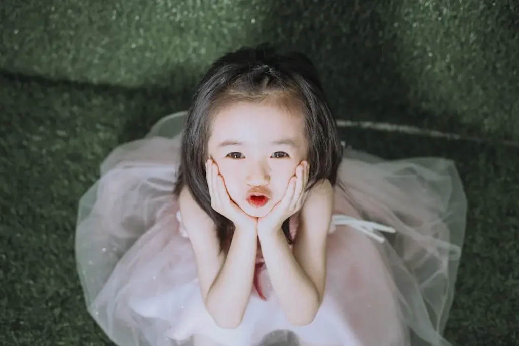 一个可爱的小女孩穿着粉色裙子双手托腮，象征紫微斗数流年运势中预测的“添丁”或“生孩子”喜事