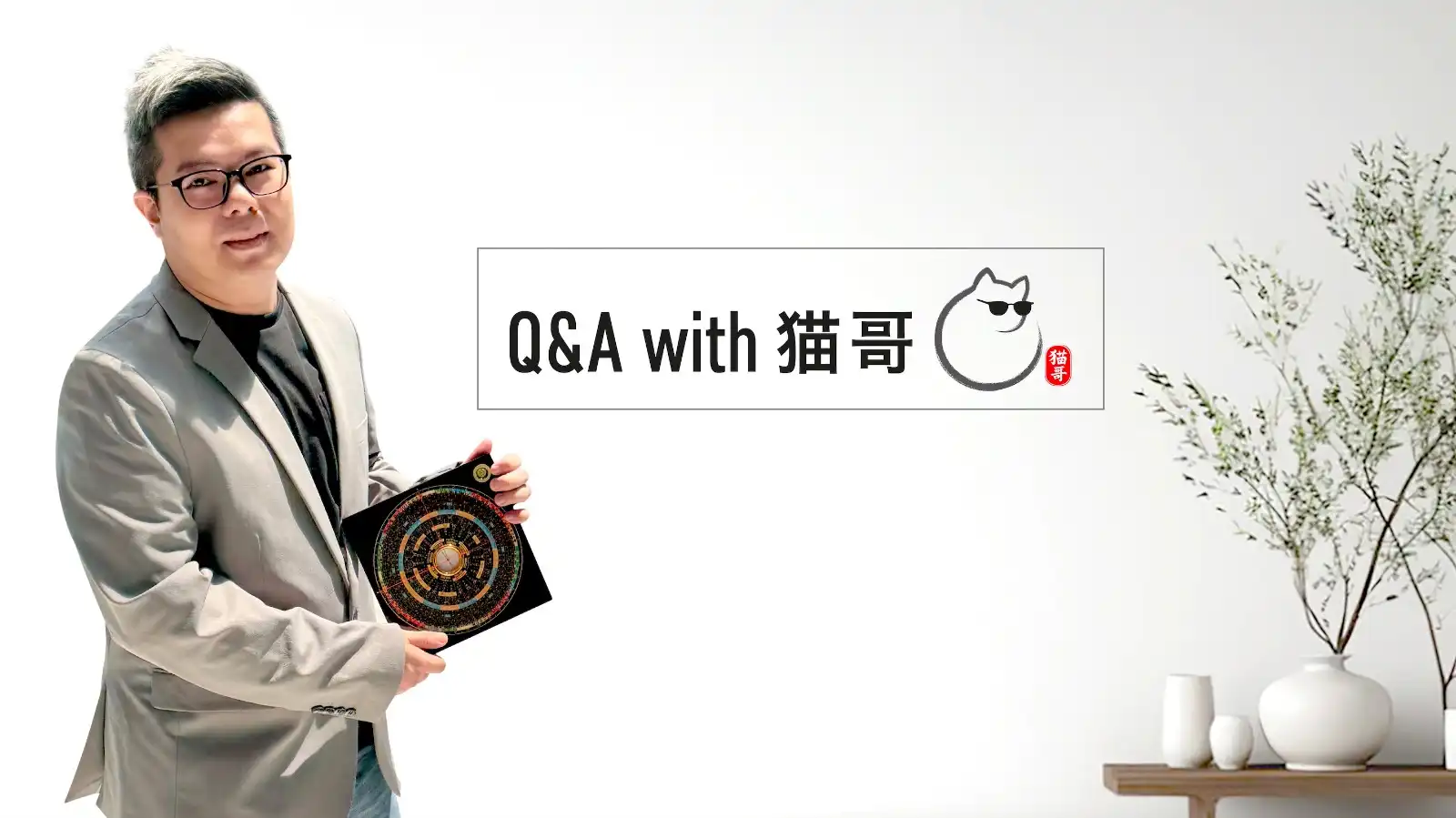猫哥风水 (LuckyCat Feng Shui) 品牌主理人猫哥，身穿灰色西装，微笑手持罗盘，解答现代风水 Q&A 咨询。